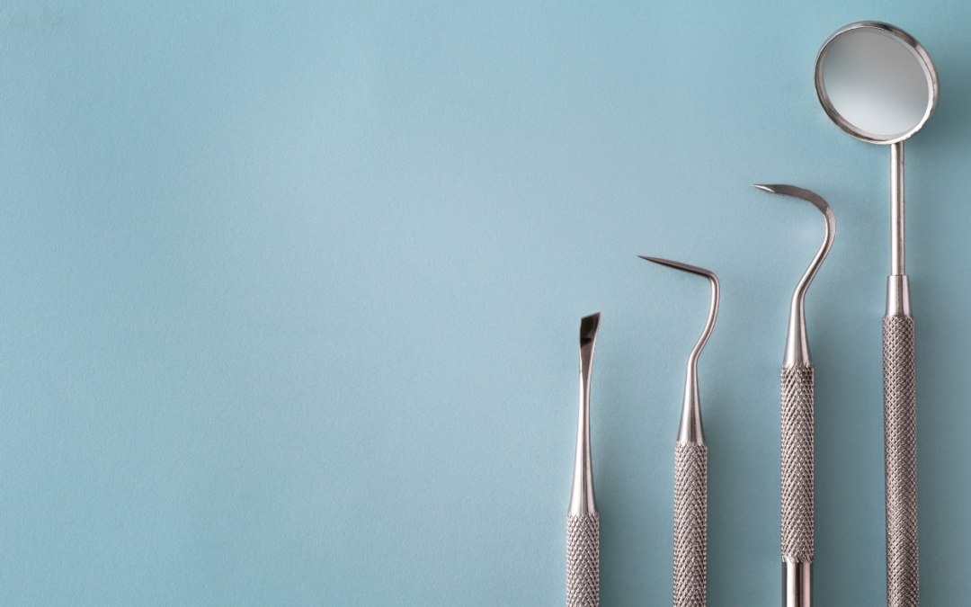 Set of metal dental instruments (scalers and mirror) aligned along the right on a light blue background.